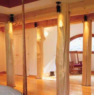 
In this nook of the master bedroom, a few of the home’s thirty-nine vertical wood supports are visible. Thirteen are from the site; the remaining trees are from elsewhere in Vermont. Most of the floors are quarter-sawn local beech, with some maple trim. The Stickley rocker is positioned to take advantage of natural light.
